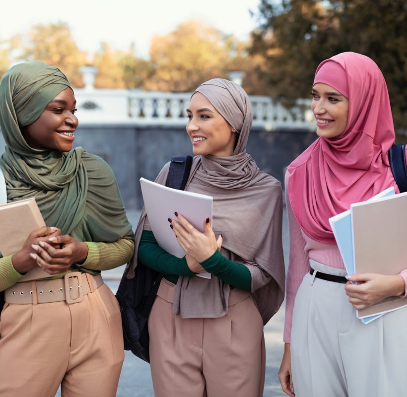 Three Muslim Female Students In Hijab Holding Books Standing Outdoors